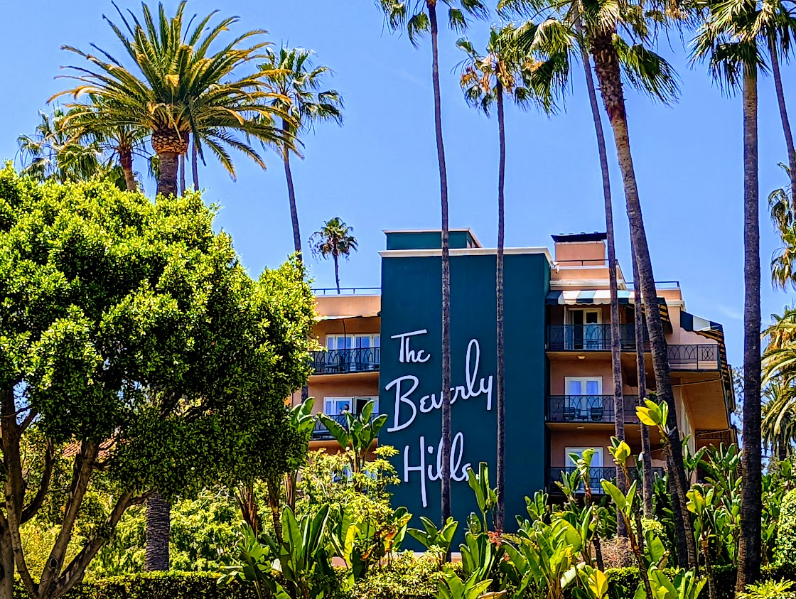 The Beverly Hills Hotel exterior sign framed by palm trees on Sunset Boulevard